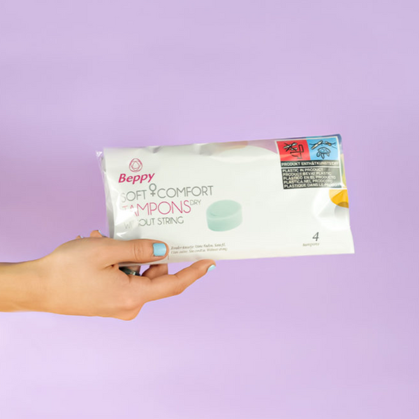 A hand holding pack of blue tampons without a string