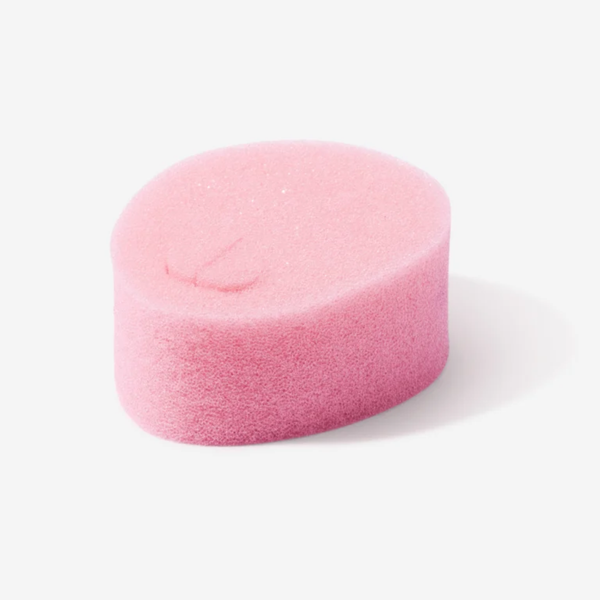 A close-up image of a single pink, oval-shaped sponge tampon. It has a soft, porous texture and a small indentation or "removal loop" visible on its top surface. The background is a clean, neutral white.