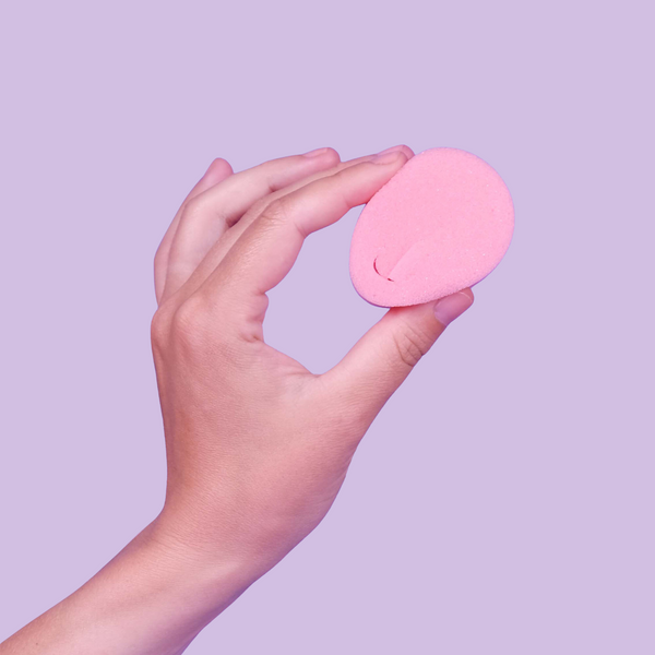 A hand holding pink tampon without a string
