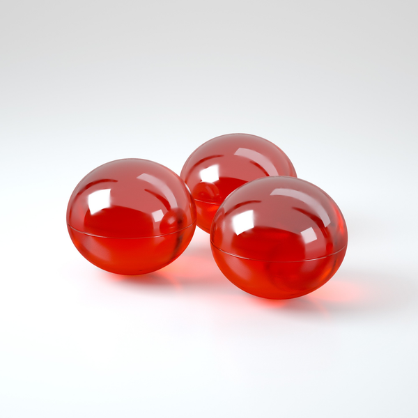 Studio product shot displaying three translucent red oil spheres grouped together on a white reflective surface.