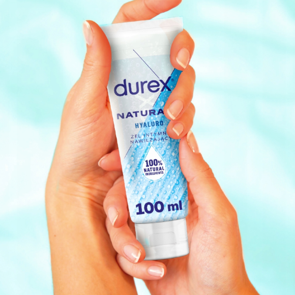 A pair of hands holding the 100ml tube of Durex Naturals Hyaluro against a soft, light blue background. The image illustrates the size of the product and its clean, modern packaging.