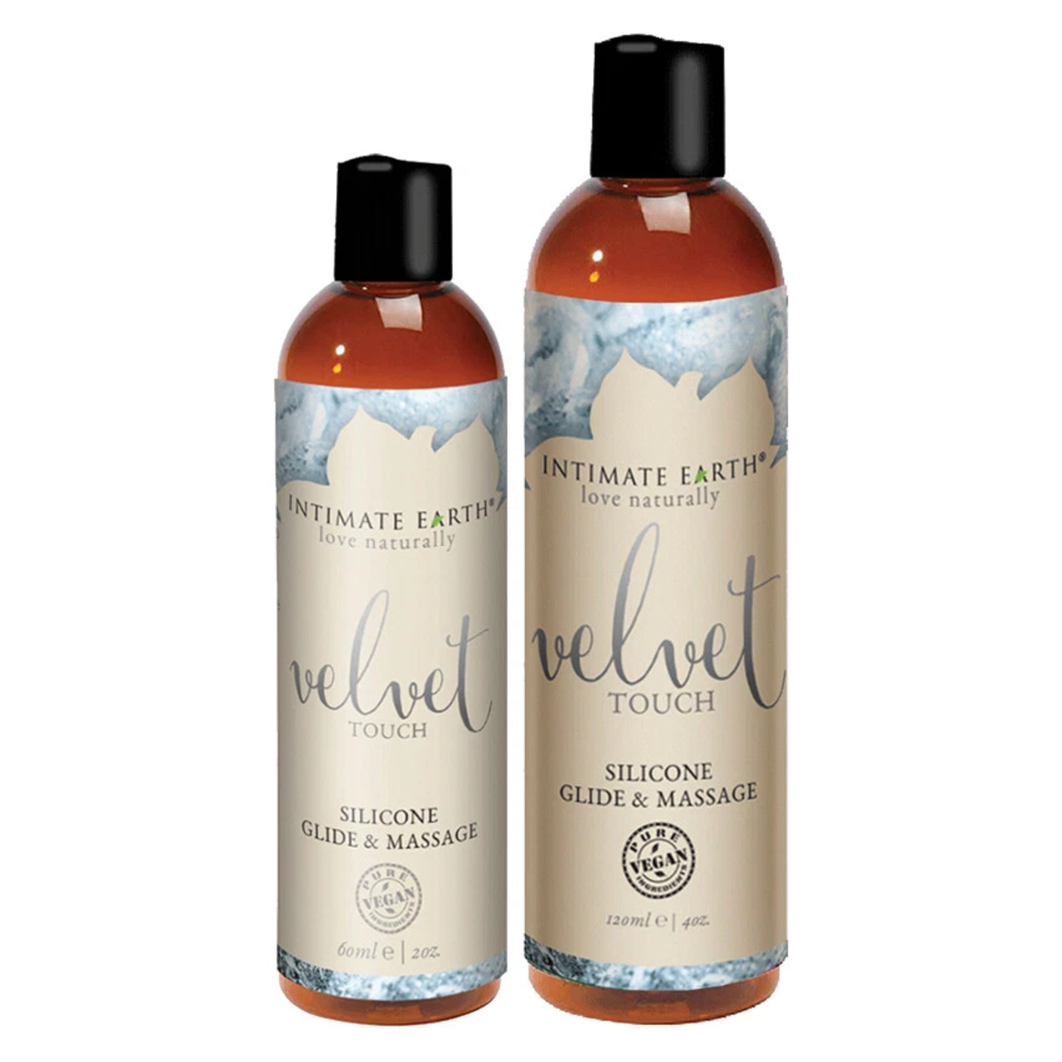 Size comparison view showing two amber bottles of Intimate Earth Velvet Touch silicone glide and massage oil standing side by side in 60 ml (2 fl oz) and 120 ml (4 fl oz) capacities. Hauptbild
