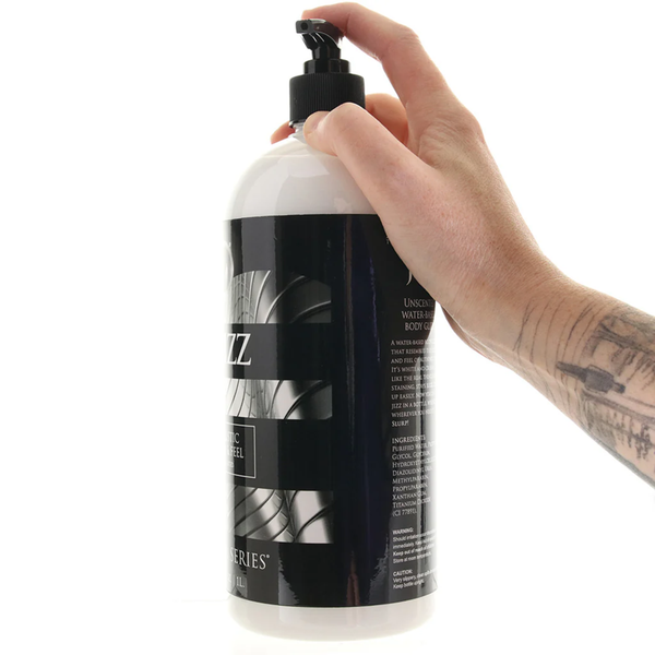 A hand pumps the dispenser of the 1 liter (34 fl. oz.) bottle of Master Series Jizz water-based body glide, showing the side label.