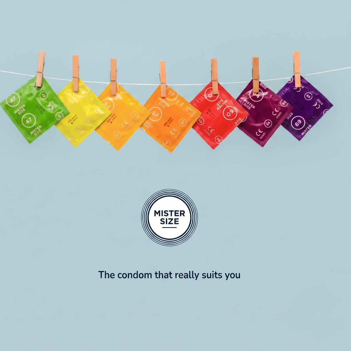 Colorful Mister Size condom wrappers in different sizes hang from clothespins on a clothesline against a light blue background. The wrappers range from green to purple and display size numbers like 47, 53, 57, 60, 64, and 69. Below them is the “Mister Size” logo with the slogan: “The condom that really suits you.