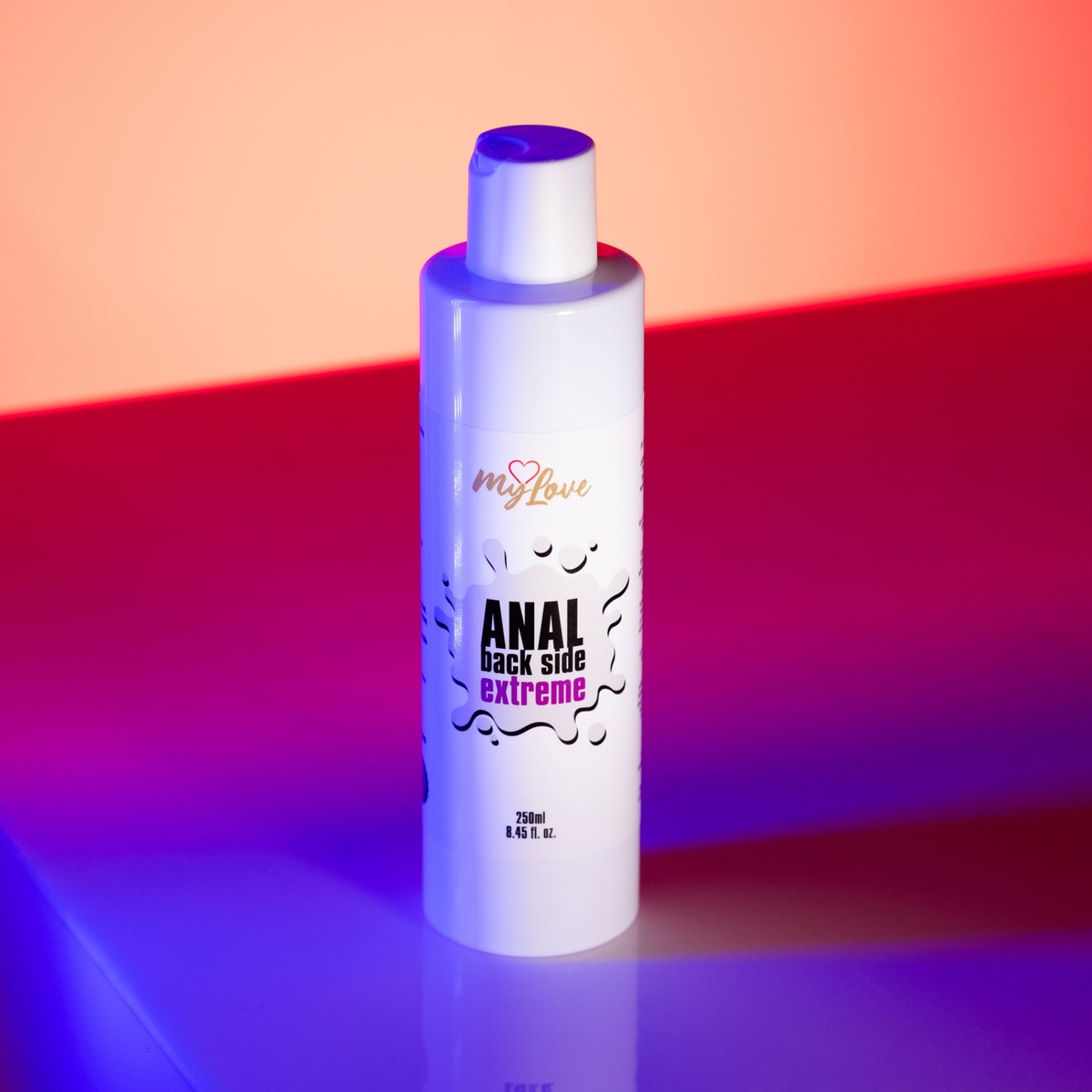 Front view of the 250 ml MyLove Anal Back Side Extreme bottle illuminated under vibrant pink and blue studio lighting.