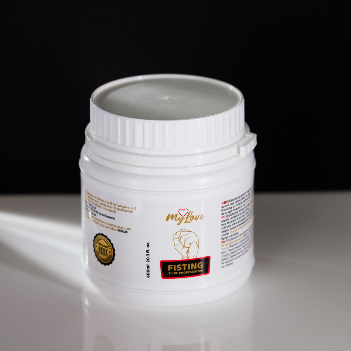 High-angle view of the 600 ml MyLove Fisting Slide Professional gel tub standing on a white reflective surface against a solid black backdrop.