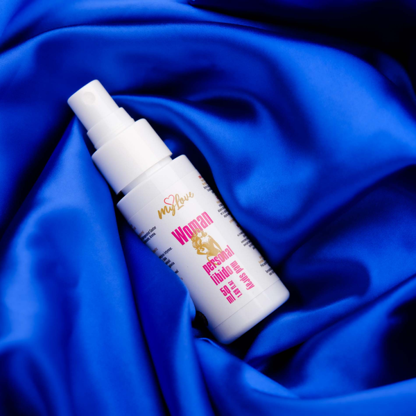 The 50 ml bottle of MyLove Woman Personal Libido Med Spray rests diagonally on draped, rich royal blue satin fabric.