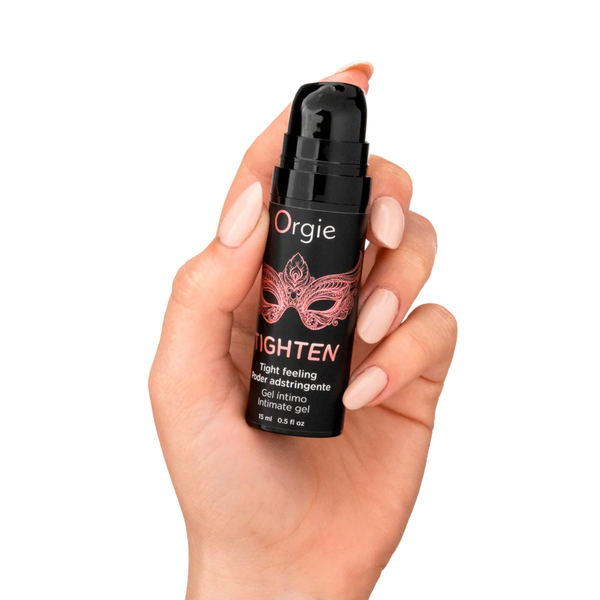 A person's hand with light pink nails holding the small black pump bottle of Orgie Tighten intimate gel.