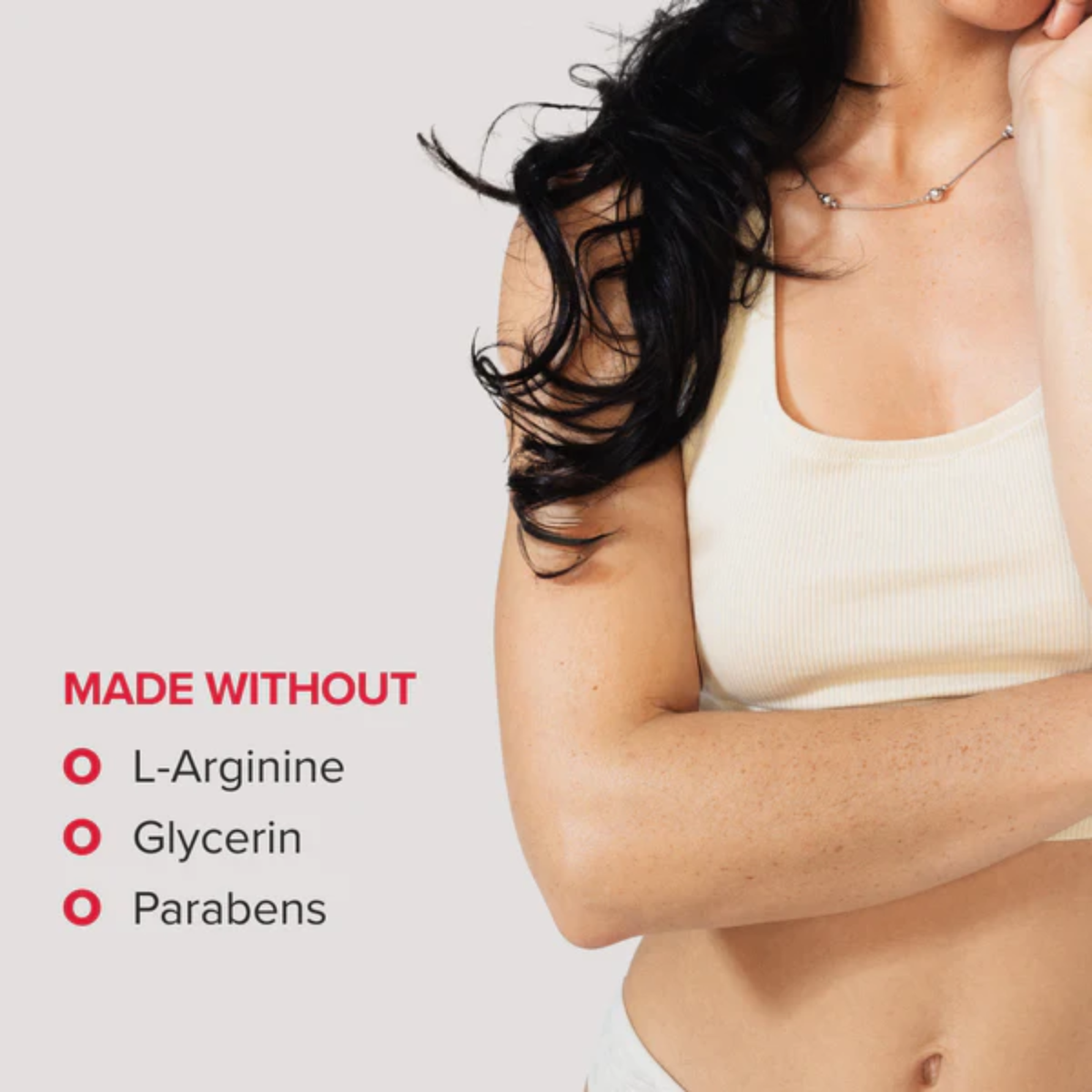 Promotional image featuring a cropped shot of a woman with long dark hair in a cream-colored tank top. On the left, red text lists that the product is "MADE WITHOUT" L-Arginine, Glycerin, and Parabens.