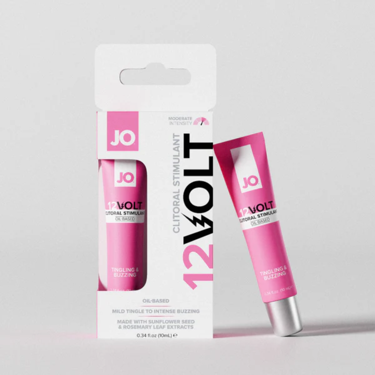 A promotional product shot showing the System JO 12VOLT box standing upright next to its matching pink tube. The tube leans against the right side of the white packaging against a plain light grey backdrop.