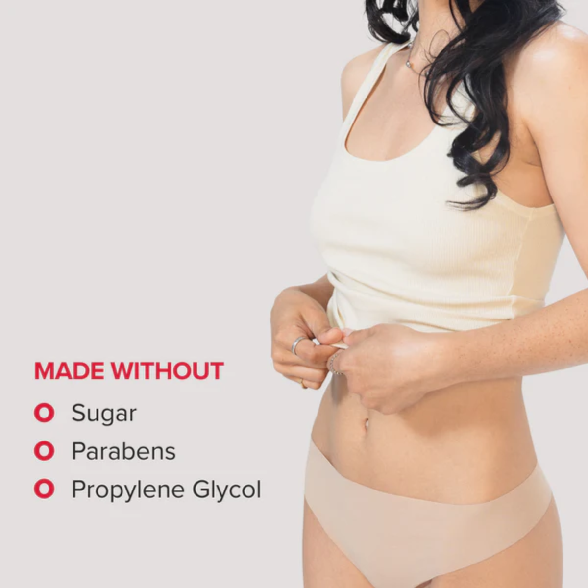 A cropped image of a woman with long dark hair wearing a cream-colored tank top. Red bullet points on the left indicate that the product is "MADE WITHOUT" sugar, parabens, or propylene glycol.