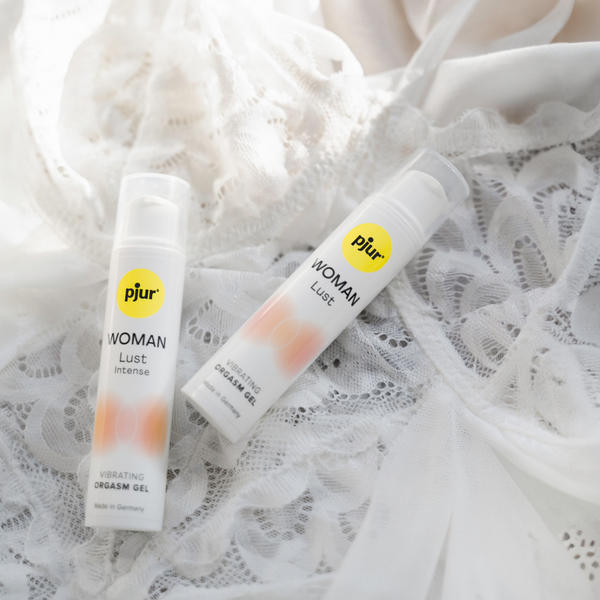 Two tubes of pjur WOMAN Lust vibrating orgasm gel on white lace.